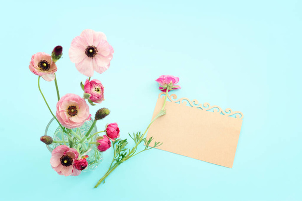 Top view image of pink flowers composition and empty note over blue pastel background - 写真・画像