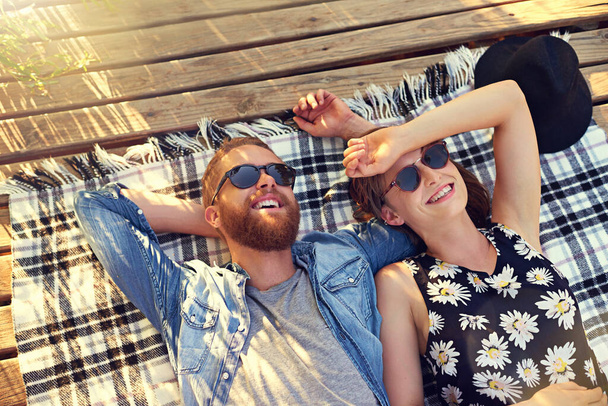 C'est le meilleur jour d'été. Prise de vue d'un jeune couple affectueux allongé sur une couverture à l'extérieur. - Photo, image