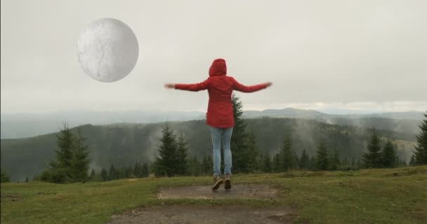 woman sees a huge unreal moon in the sky. Gives signals to aliens. Rotating planet, mountains, forest, fog, daytime - Séquence, vidéo