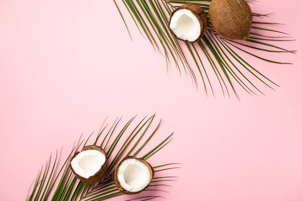 Summer concept. Top view photo of tropical fruits coconuts and palm leaves on isolated pastel pink background with copyspace - Fotografie, Obrázek