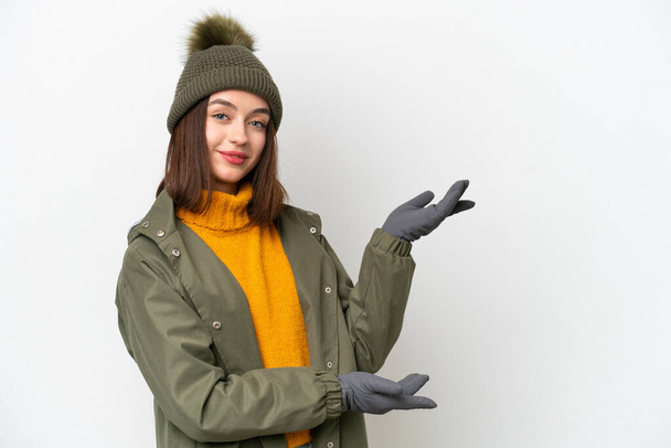 Young Ukrainian woman wearing winter jacket isolated on white background extending hands to the side for inviting to come - Fotografie, Obrázek
