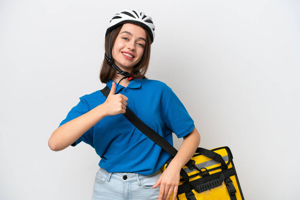 Young Ukrainian woman with thermal backpack isolated on white background giving a thumbs up gesture - 写真・画像