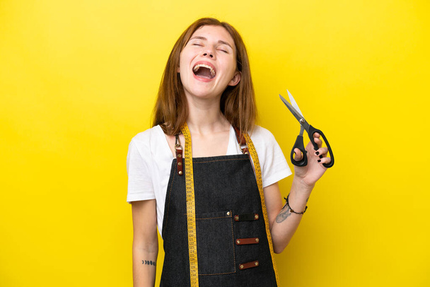 Jonge naaister Engels vrouw geïsoleerd op gele achtergrond lachen - Foto, afbeelding