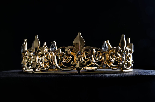 крупным планом красивая настоящая золотая корона, изолированная на темном черном студийном фоне. - Фото, изображение