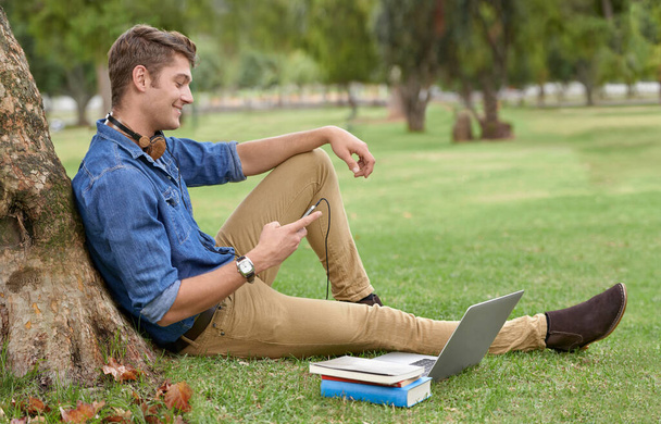 Краще за будь-яку бібліотеку. Знімок красивого молодого чоловіка, який навчається в парку з ноутбуком
. - Фото, зображення