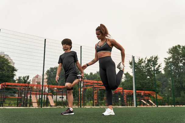 Caucasian athletic mother help son stretch leg - 写真・画像