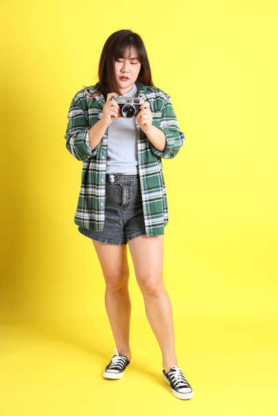 The chubby Asian woman standing on the yellow background with the casual clothes. - Foto, immagini