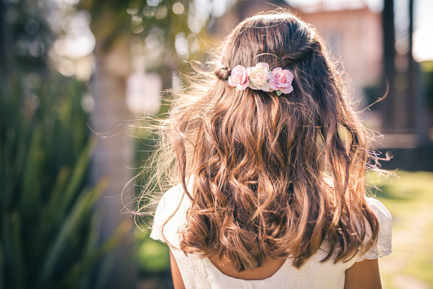 Cabelo de flor de uma primeira menina comunhão com as costas virado em um parque - Foto, Imagem