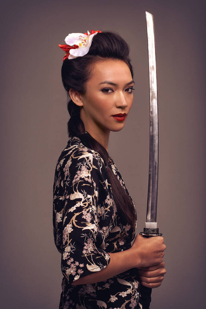 Hän on verraton miekan kanssa. Studio laukaus viehättävä nuori nainen kädessään samurai miekka. - Valokuva, kuva