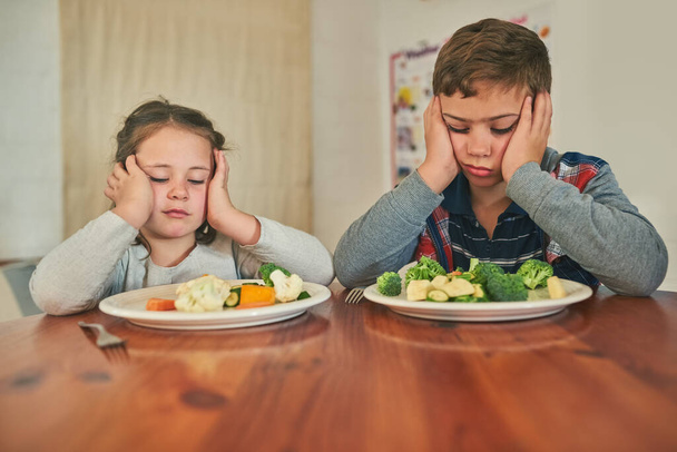 Wed rather go on a hunger strike. Cropped shot of two grumpy children refusing to eat their vegetables. - Photo, image
