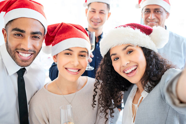 Kerstmis brengt ons allemaal samen. Opname van een groep zakenmensen die een selfie maken op het werk. - Foto, afbeelding