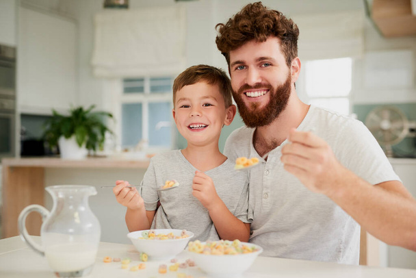 Het ontbijt wordt beter gedeeld met papa. Shot van een schattige kleine jongen en zijn vader ontbijten samen thuis. - Foto, afbeelding
