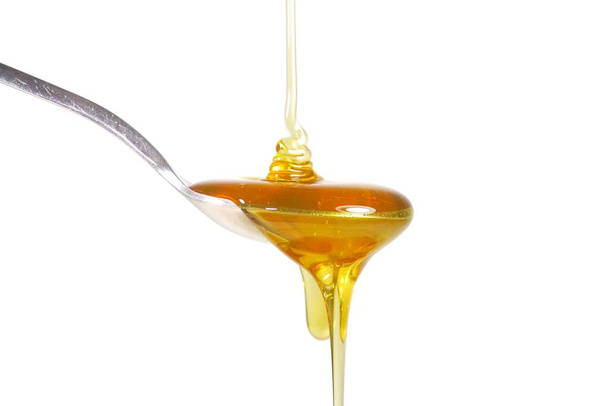 Image of honey on a spoon on a white background - Fotoğraf, Görsel