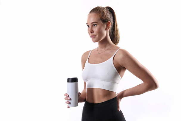 Fitness woman drinking water from a bottle. Beautiful athletic girl on the white background - Photo, Image