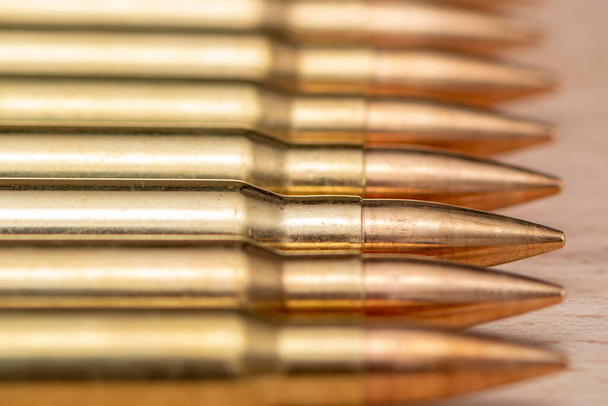 A row of cartridges with 7.62 caliber bullets for a Kalashnikov assault rifle on a textured background, close-up, selective focusing. Concept: sale of weapons under lend-lease, assistance with weapons and ammunition, arms supplies. - 写真・画像