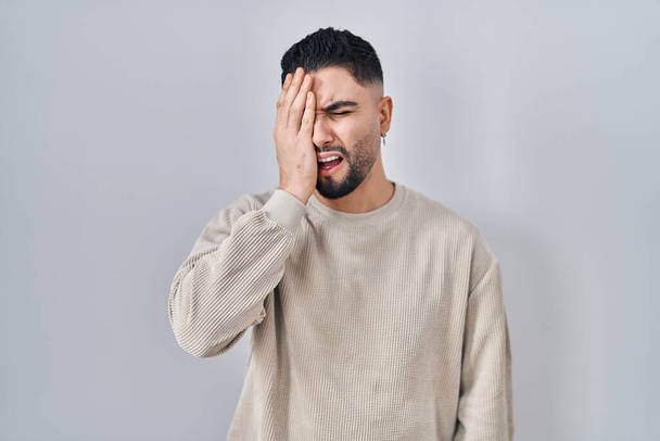 Young handsome man standing over isolated background yawning tired covering half face, eye and mouth with hand. face hurts in pain.  - Photo, Image