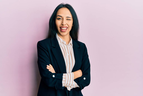 Young hispanic girl wearing business clothes with arms crossed winking looking at the camera with sexy expression, cheerful and happy face.  - Fotoğraf, Görsel