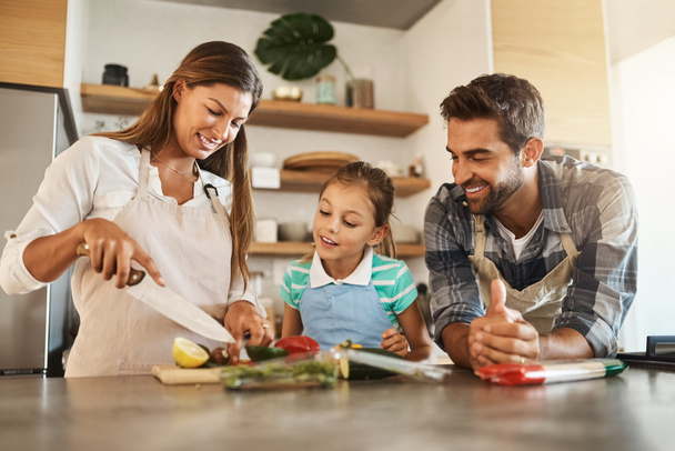 Leren van de beste. Shot van een gelukkig jong gezin koken samen in hun keuken thuis. - Foto, afbeelding