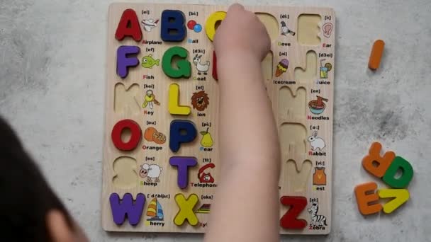 Vista superior de un niño jugando al rompecabezas del alfabeto y aprendiendo inglés en el suelo. - Metraje, vídeo