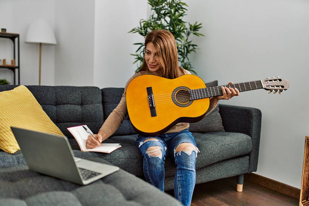 Middle age caucasian woman writing lyrics song sitting on the sofa at home. - Photo, Image