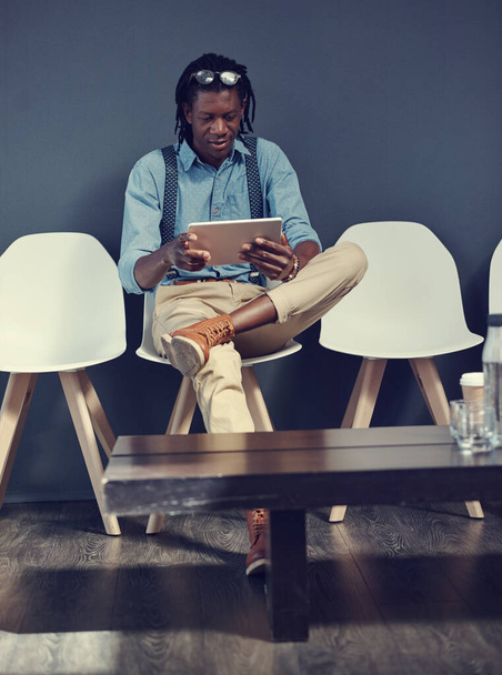 Kihasználom ezt az időt, hogy felzárkózzak a közösségi médiához. Egy fiatal üzletemberről, aki táblagépet használ, miközben egy interjúra vár.. - Fotó, kép