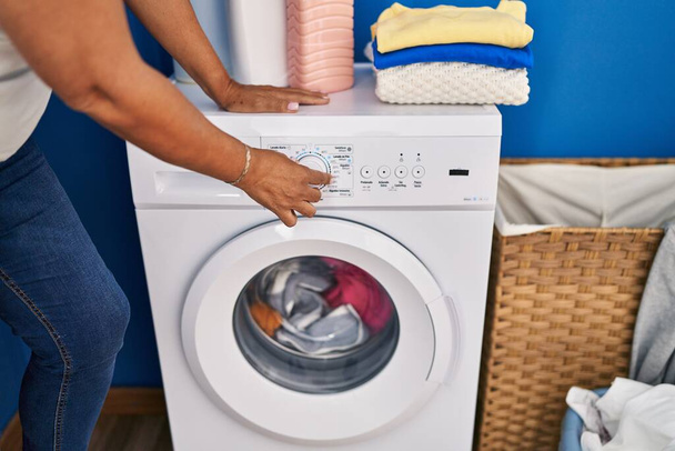 Mujer hispana de mediana edad lavando ropa en la lavandería - Foto, imagen