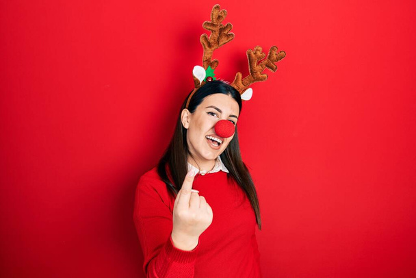Young hispanic woman wearing deer christmas hat and red nose beckoning come here gesture with hand inviting welcoming happy and smiling  - Valokuva, kuva