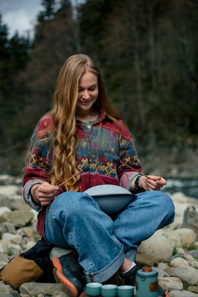 νεαρή γυναίκα κάθεται σε ένα παγκάκι και παίζει το γλυκόφωνο - Φωτογραφία, εικόνα