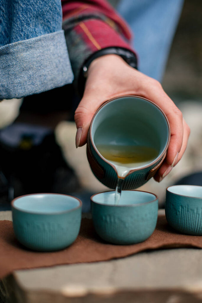 ženy ruce drží šálek čaje a konvici na dřevěném stole - Fotografie, Obrázek