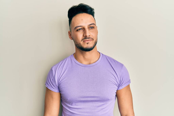 Young arab man wearing casual clothes looking to side, relax profile pose with natural face and confident smile.  - Фото, зображення