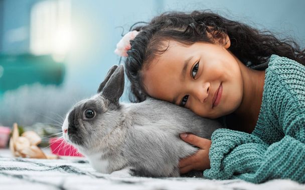 Hes my best friend. Shot of an adorable little girl bonding with her pet rabbit at home. - Фото, зображення