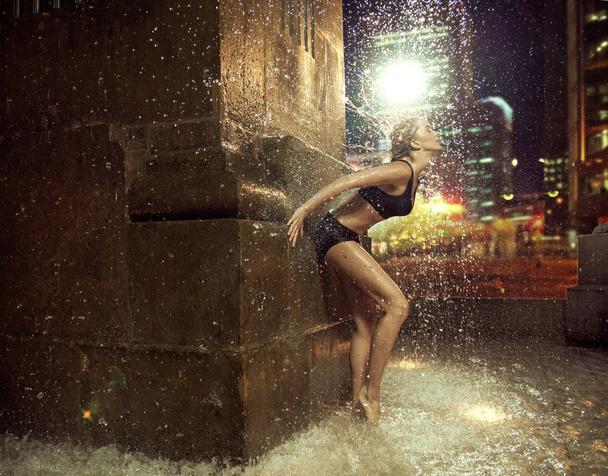 Fit woman making a figure in a fountain - Foto, imagen