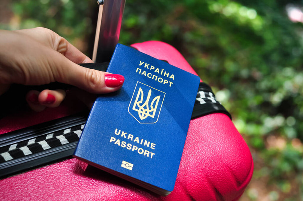 Biometric Ukrainian passport of refugee on pink Travel bag - Fotó, kép