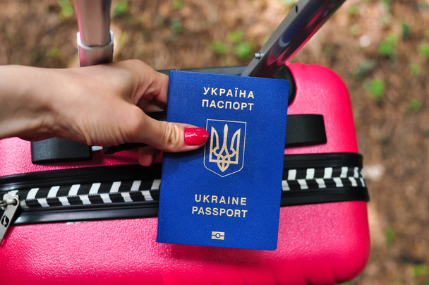 Biometric Ukrainian passport of refugee on pink Travel bag - Foto, imagen