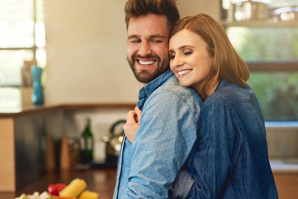 Si cocina para ti, es un guardián. Foto de una feliz pareja joven compartiendo un momento cariñoso en la cocina en casa. - Foto, imagen