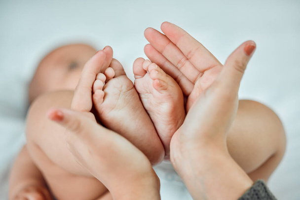 A legkisebb lábak hagyják a legnagyobb lábnyomokat a szíveden. Közelkép egy nőről, aki felemeli a babáit apró lábakkal.. - Fotó, kép