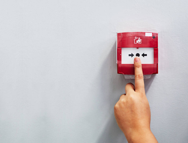 Activating the alarm. Cropped shot of a person pressing a fire alarm on a wall. - Photo, Image