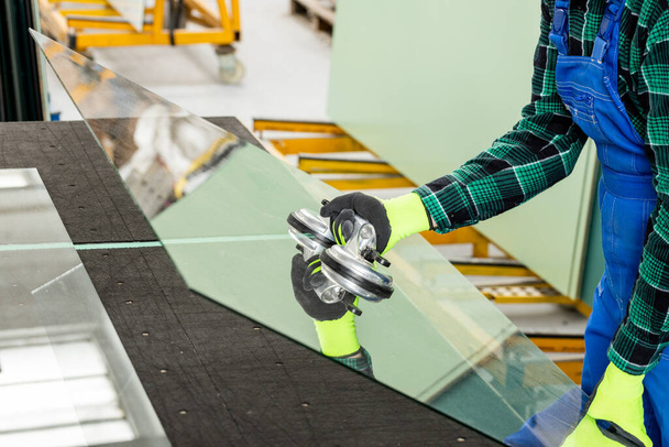 Specialista na sklářskou společnost odstraňuje velkou tabuli skla ze stolu pomocí speciálního přísavkového kelímku ze skla, skláře, který vykonává práci   - Fotografie, Obrázek