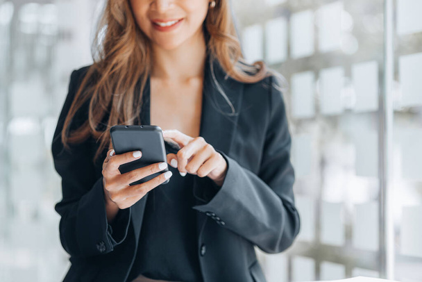 Молодая предпринимательница, глядя на финансовую информацию с мобильного телефона, проверяет финансовые документы компании, является исполнительной женщиной стартап-компании. Концепция финансового управления. - Фото, изображение