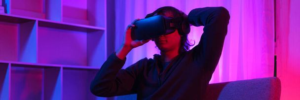 Metaverse έννοια της τεχνολογίας, ο άνθρωπος κρατώντας γυαλιά VR και να διασκεδάσουν surround φουτουριστικό σε metaverse. - Φωτογραφία, εικόνα