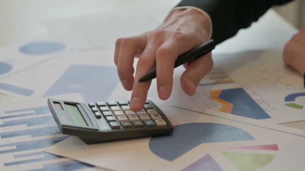 Крупним планом середнього віку бізнесмен пише на папері, використовуючи калькулятор
 - Кадри, відео