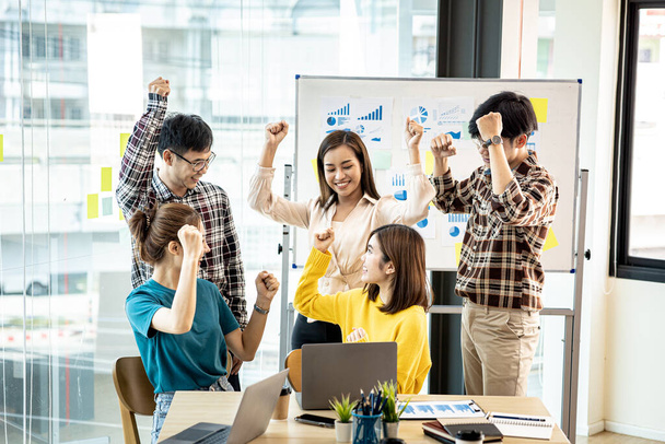 A group of startup company employees are in the conference room, raising their hands to show their appreciation after looking at the company's sales and profitable results. Startup company concept. - Foto, Imagem