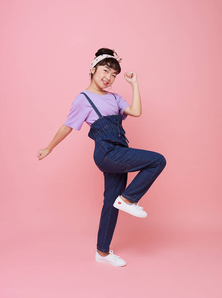 Cheerful Asian child girl celebrate with raised fists looking at camera isolated on pink background. - Photo, Image