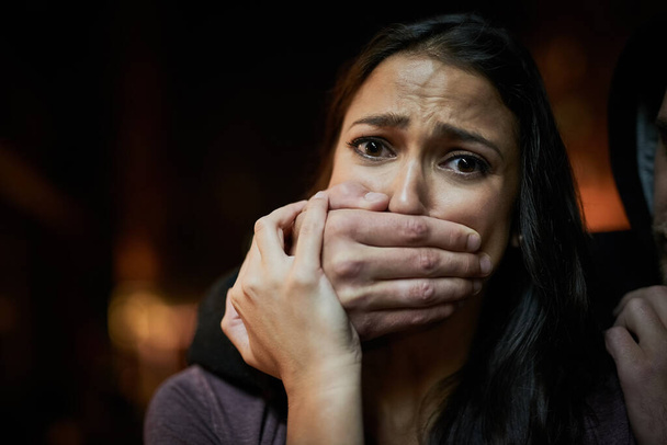 Wehrlos und in Gefahr. Porträt einer verängstigten jungen Frau mit der Hand über dem Mund der Angreifer. - Foto, Bild