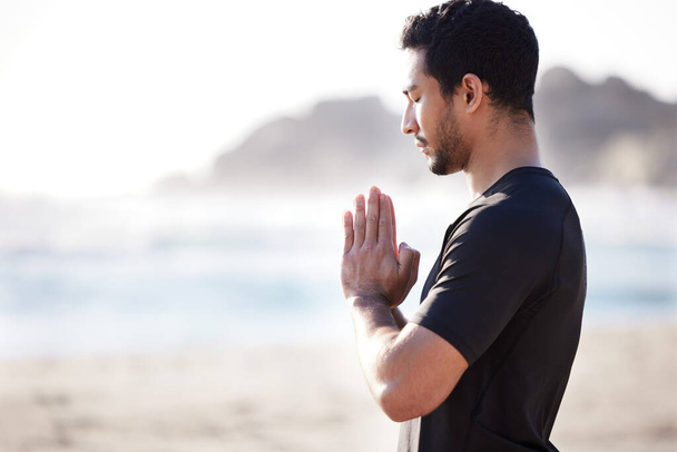 Calm your mind. Cropped shot of a handsome young male athlete meditating on the beach. - Foto, Imagem