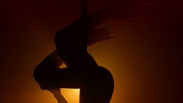 Mujer silueta realizando poledance en el centro de atención. Chica bailando seductora. - Foto, Imagen