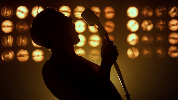 Sänger performen Song feurig auf der Bühne Nahaufnahme. Silhouette unbekannter Mann - Foto, Bild