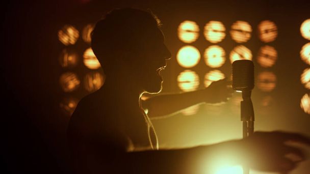 Silhouette unknown performer singing in club closeup. Vocalist performing firely - Fotó, kép