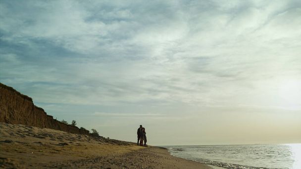 人々はビーチの風景立ってグループ。波の衝突による家族の散歩日没の海. - 写真・画像