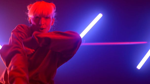 Girl hiphop dancer moving body emotionally in ultraviolet backlit close up.  - Foto, imagen
